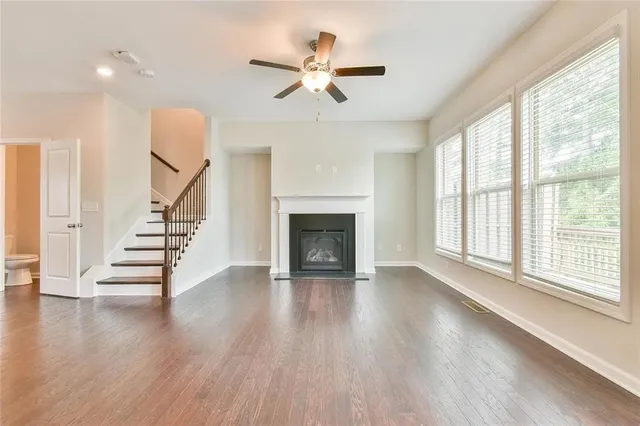 a view of an empty room with wooden floor fireplace and a window