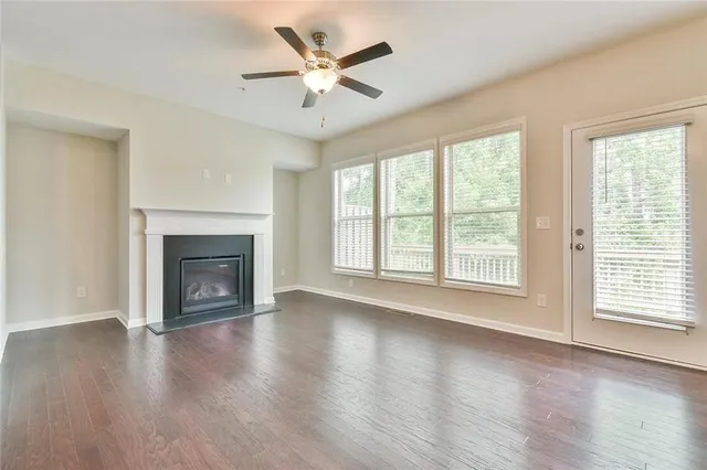 an empty room with wooden floor fireplace and windows