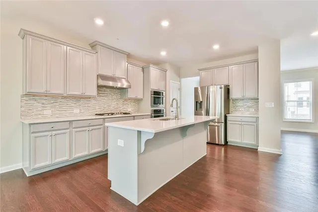 a kitchen with stainless steel appliances granite countertop a refrigerator sink and white cabinets