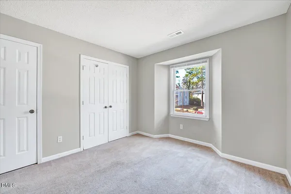 a view of an empty room with window and closet area