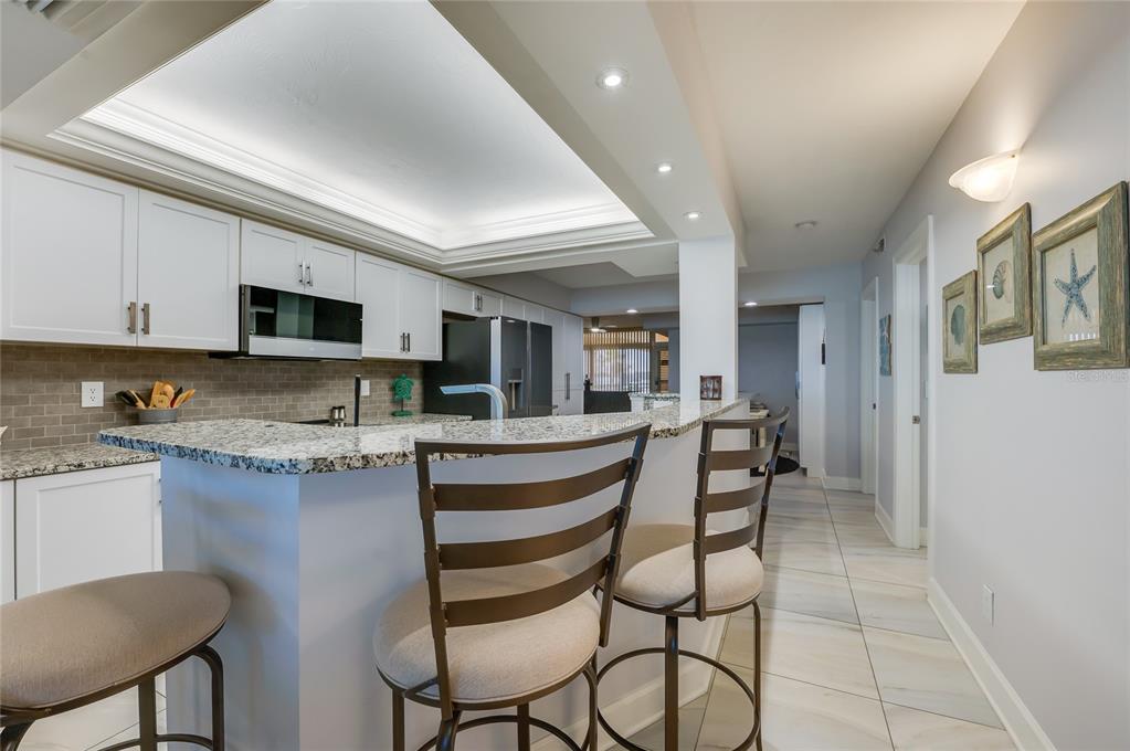 4575 South Atlantic Avenue, Unit 6304 Ponce Inlet, FL 32127 - Photo 11 of 37 a kitchen with stainless steel appliances granite countertop a stove top oven a sink a dining table and chairs
