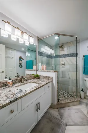 a bathroom with a granite countertop sink mirror and shower