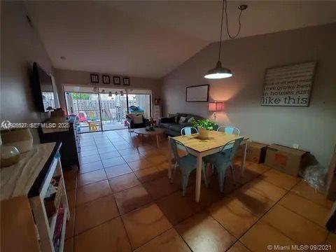 14927 Southwest 89th Street, Unit 14927 Miami, FL 33196 - Photo 5 of 12 a living room with furniture a flat screen tv and a dining table with a kitchen island