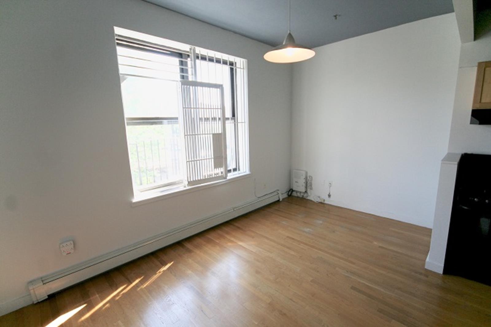 47-45 Vernon Boulevard, Unit 3C Queens, NY 11101 - Photo 5 of 6 an empty room with wooden floor and windows