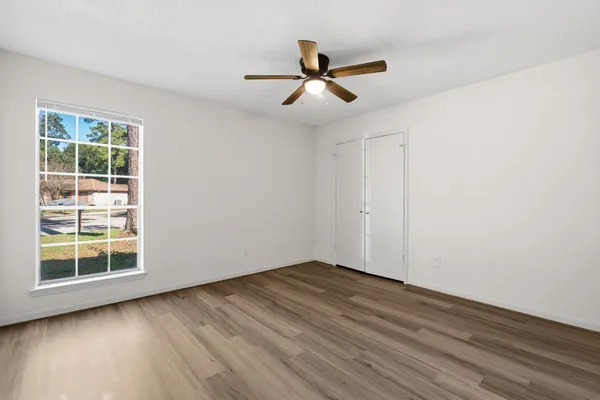 a view of empty room with wooden floor and fan