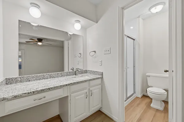 a spacious bathroom with a granite countertop sink a toilet and a shower