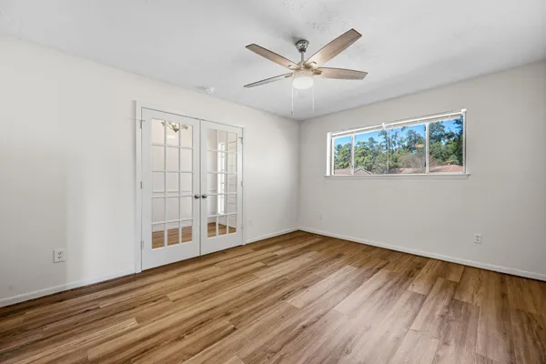 a view of an empty room with wooden floor and a window