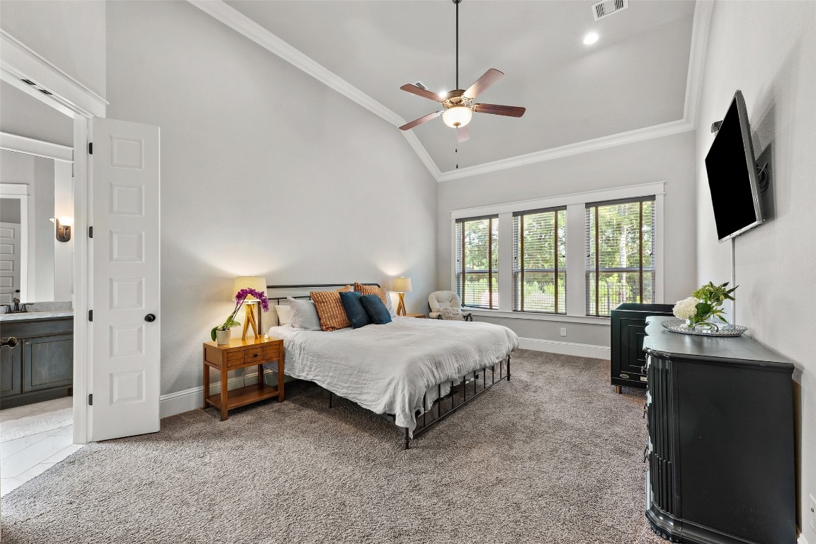 2172 Rope Maker Road Conroe, TX 77384 - Photo 19 of 50 The primary bedroom features a high ceiling with a ceiling fan, large windows providing natural light that also has a beautiful view of nature reserve....what a difference this beautiful view and privacy make in enjoying your home!