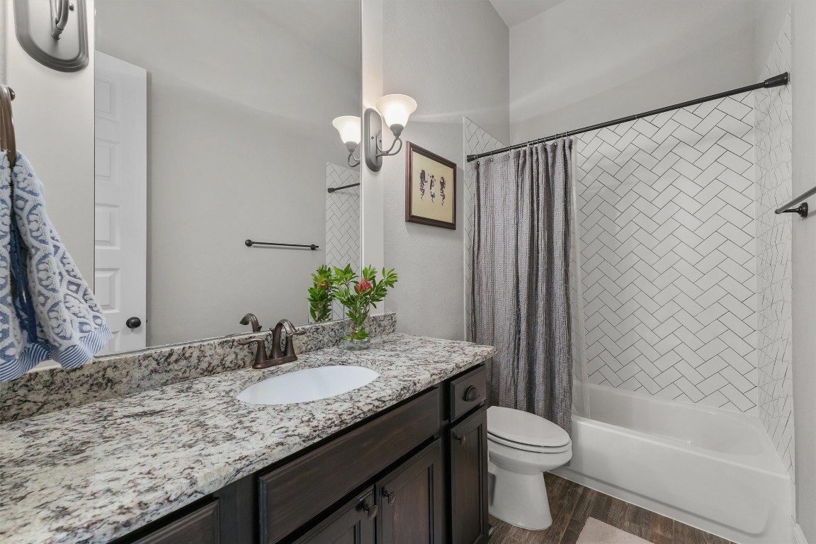 2172 Rope Maker Road Conroe, TX 77384 - Photo 28 of 50 Full Secondary bathroom features a modern design with beautiful countertop, stained wood vanity, and a sleek undermount sink. The shower area is accented with a herringbone tile pattern. Bright and inviting, perfect for a stylish, functional bathroom space.