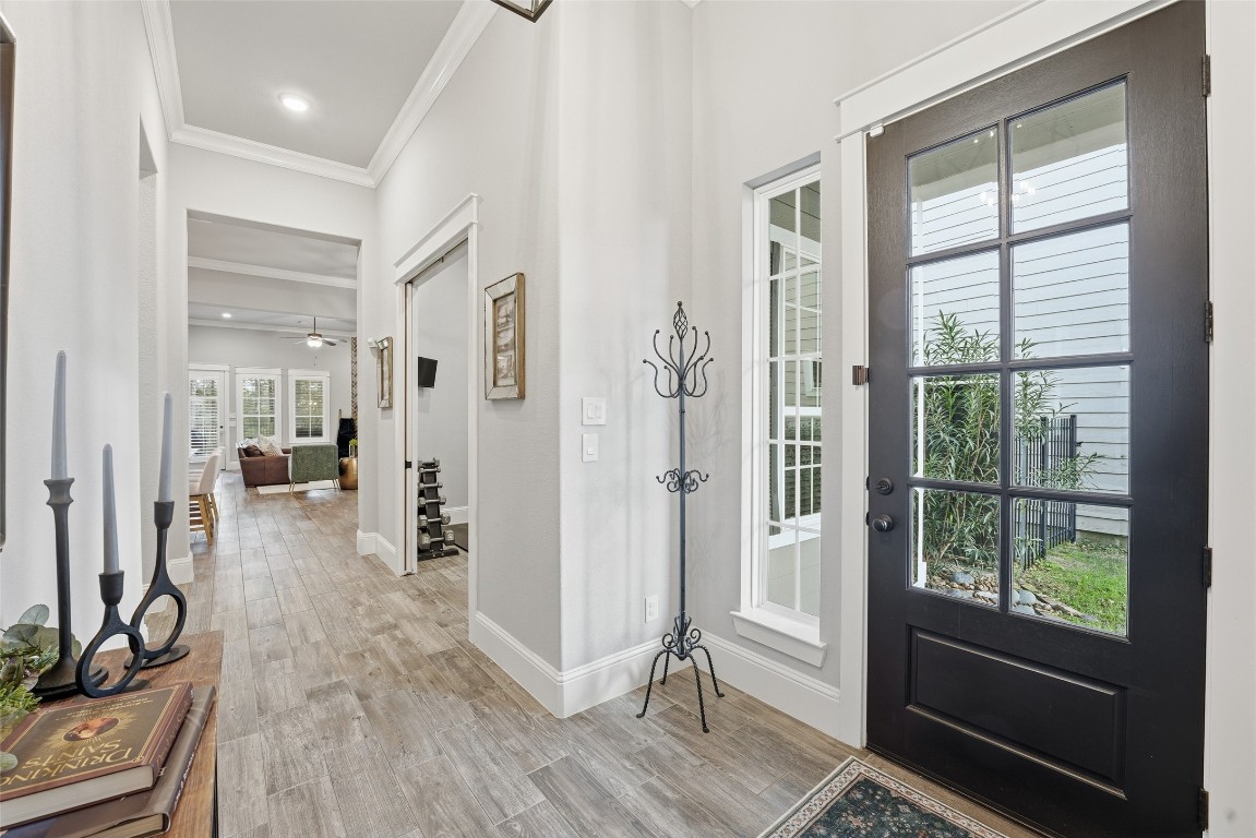2172 Rope Maker Road Conroe, TX 77384 - Photo 8 of 50 Bright, welcoming entryway with a glass-panel front door and side window. The hallway has durable light wood-style flooring and leads into a spacious living area with ceiling fans and large windows, allowing plenty of natural light. Elegant decor and neutral walls add to the inviting atmosphere.