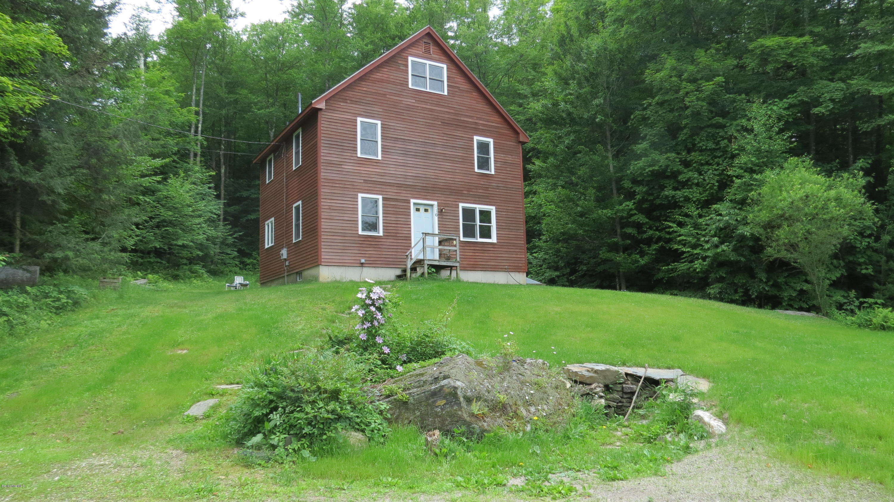 a front view of a house with a yard and trees