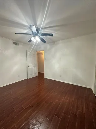 an empty room with wooden floor fan and windows