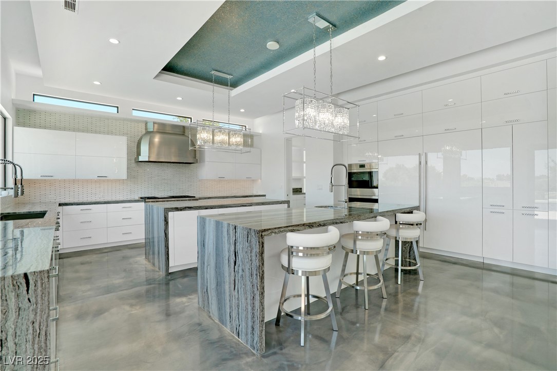10 Ridge Blossom Road Las Vegas, NV 89135 - Photo 14 of 69 Kitchen with dark stone countertops, white cabinetry, hanging light fixtures, modern cabinets, and a kitchen breakfast bar