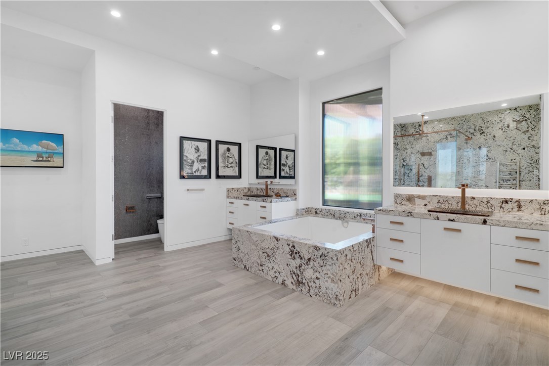 10 Ridge Blossom Road Las Vegas, NV 89135 - Photo 24 of 69 Full bath featuring two vanities, a marble finish shower, a garden tub, recessed lighting, and light wood-type flooring
