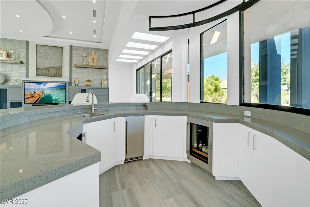 10 Ridge Blossom Road Las Vegas, NV 89135 - Photo 9 of 69 Bar area featuring wine cooler, dark stone countertops, white cabinetry, light wood finished floors, and recessed lighting