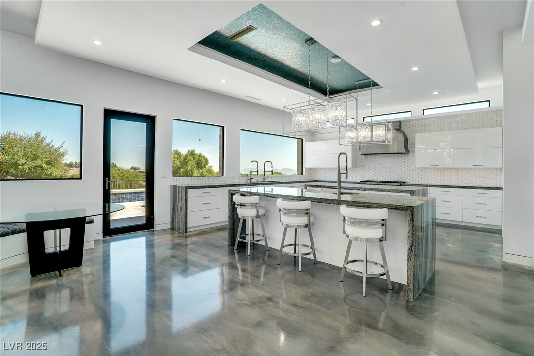 10 Ridge Blossom Road Las Vegas, NV 89135 - Photo 10 of 69 Kitchen featuring dark stone countertops, white cabinets, an island with sink, a breakfast bar, and recessed lighting