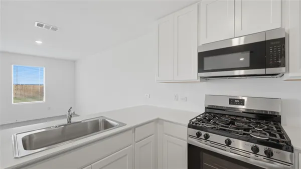a kitchen with granite countertop a sink stainless steel appliances and cabinets