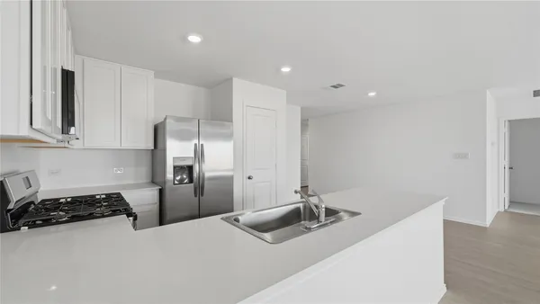 a kitchen with stainless steel appliances a sink a stove a refrigerator and cabinets