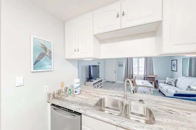a kitchen with granite countertop a sink and white cabinets