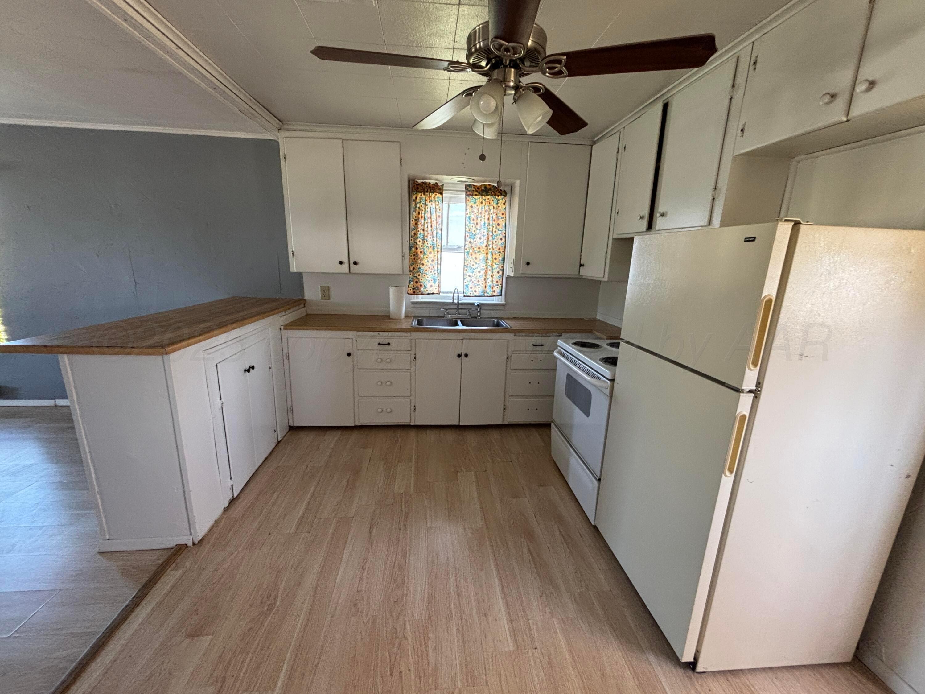 320 West Summit Street Miami, TX 79059 - Photo 14 of 19 a kitchen with granite countertop a refrigerator a sink dishwasher a stove and white countertops with wooden floor