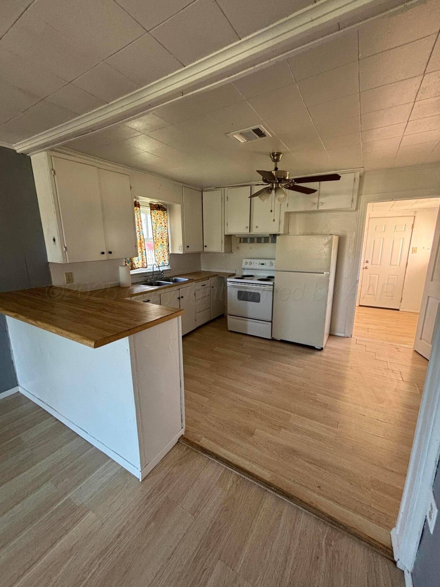 320 West Summit Street Miami, TX 79059 - Photo 15 of 19 a kitchen with granite countertop a stove and wooden floor