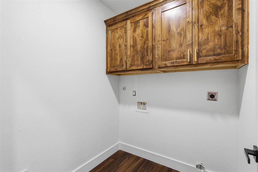 1413 Ridgeview Circle Granbury, TX 76048 - Photo 15 of 35 Laundry room featuring rich wood cabinetry with gold-tone hardware, wood-finish flooring, and white baseboards