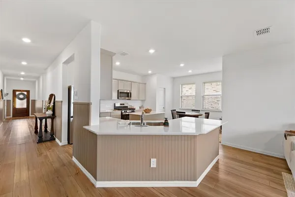 a large kitchen with stainless steel appliances granite countertop a lot of counter space and wooden floor