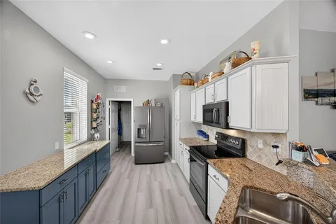 a kitchen with granite countertop a stove a sink and a refrigerator