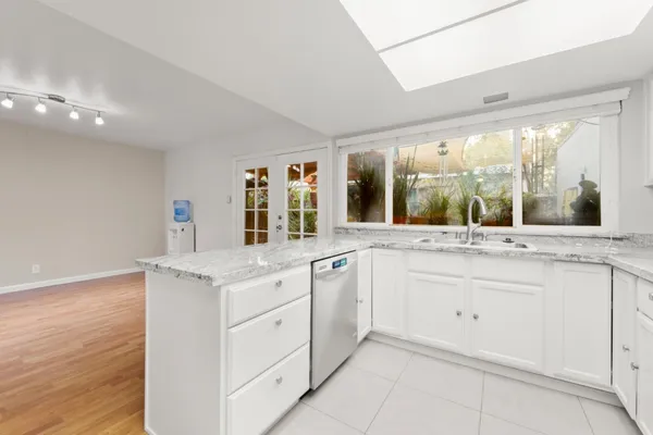 a kitchen with granite countertop a sink and white cabinets