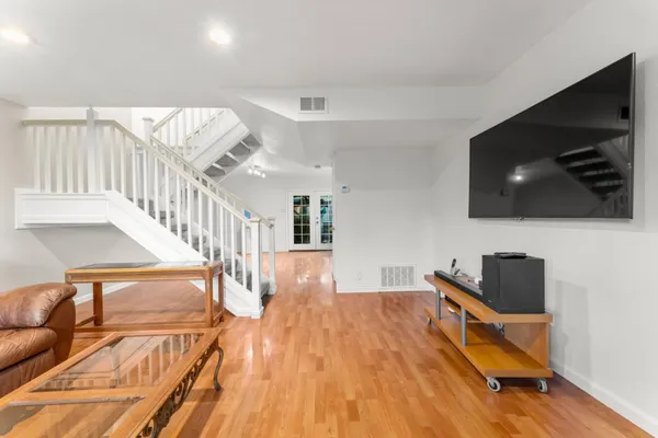a living room with wooden floor and flat screen tv