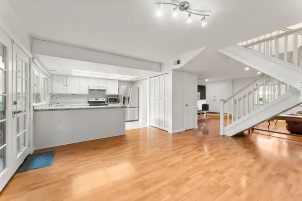 a view of an empty room and kitchen with a sink