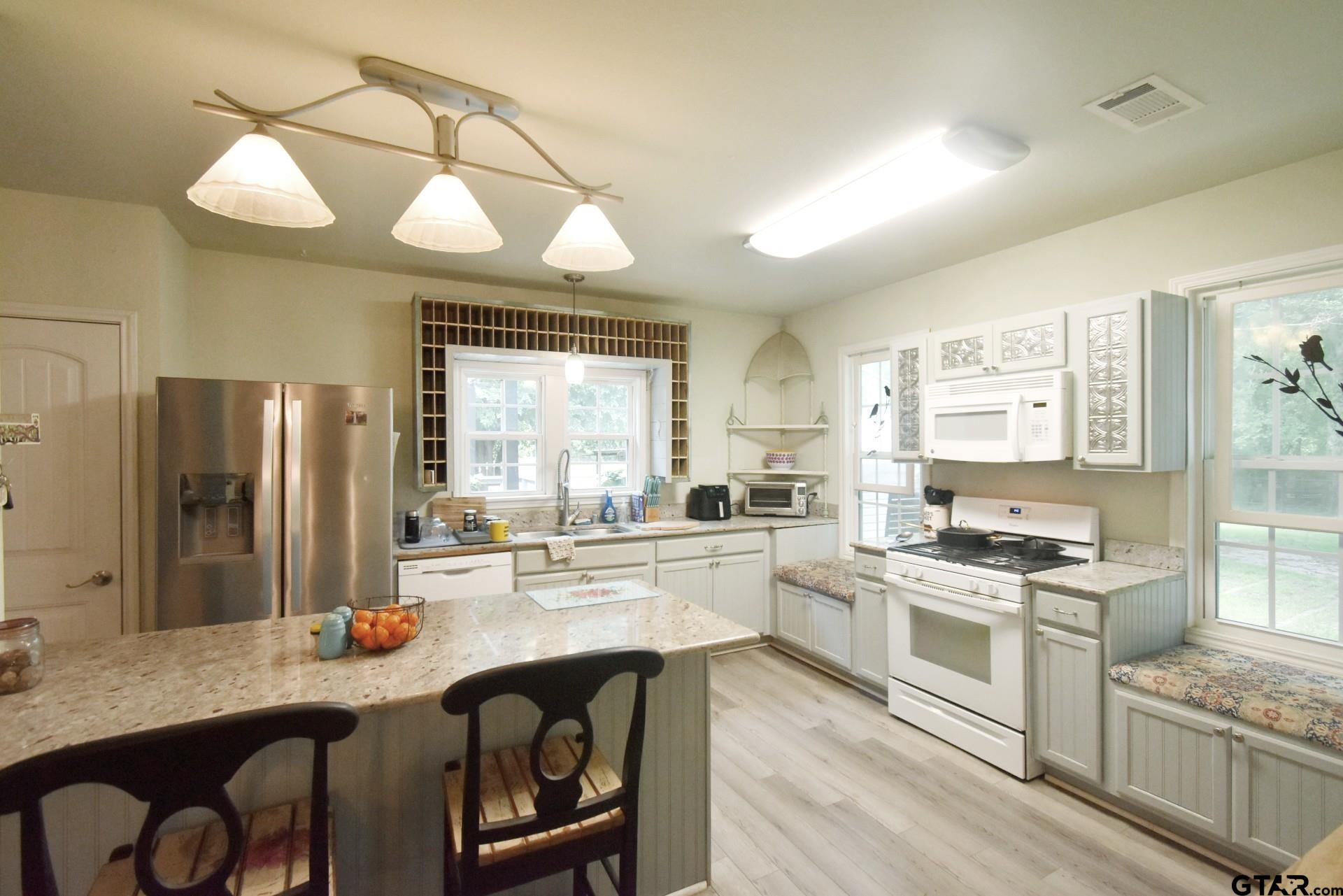 370 Spur 514 Yantis, TX 75497 - Photo 22 of 38 a kitchen with stainless steel appliances granite countertop a stove a sink dishwasher a refrigerator and wooden cabinets with wooden floor