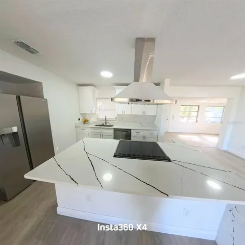 a large white room with a large bed and wooden floor