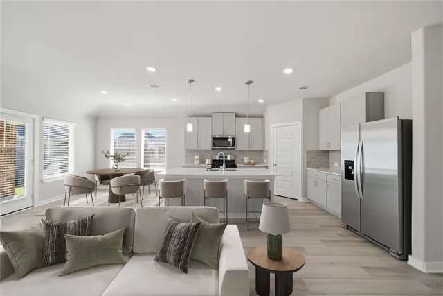 a large living room with stainless steel appliances kitchen island granite countertop a couch a dining table and chairs