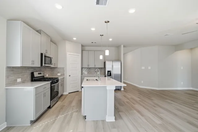 a large white kitchen with lots of counter space a sink appliances and cabinets