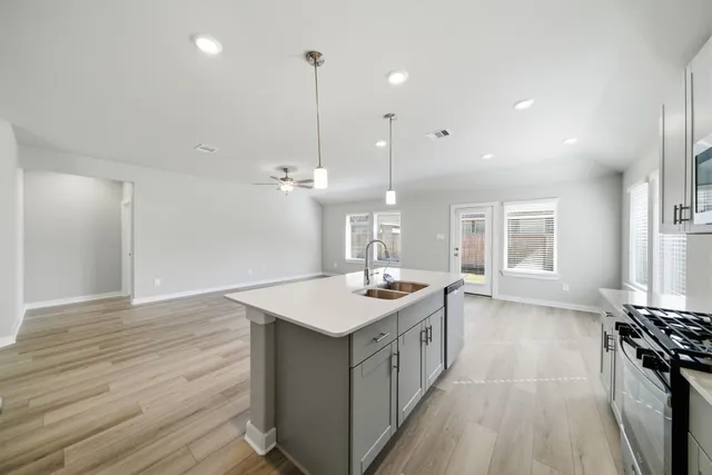 a kitchen with a stove sink and wooden floor
