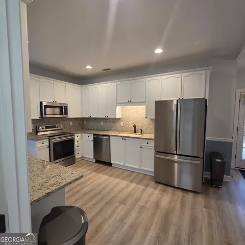 a kitchen with granite countertop a refrigerator oven a sink and dishwasher
