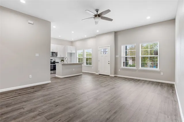 a view of an empty room with a window and wooden floor