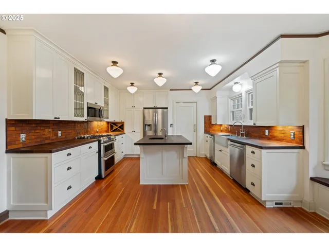 a large kitchen with stainless steel appliances lots of counter space and wooden floor