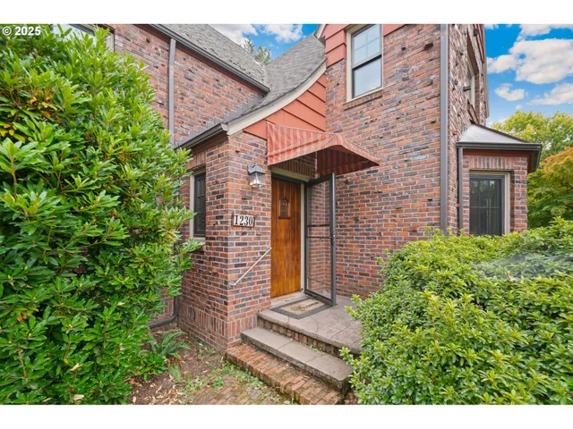 a view of a small house with plants and large tree