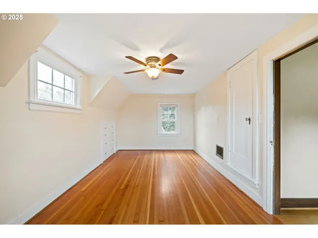 a view of an empty room with window and wooden floor