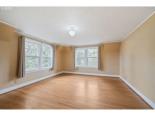 a view of an empty room with a window and wooden floor