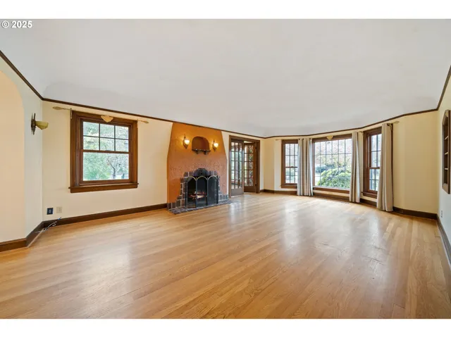 a view of an empty room with a window and wooden floor