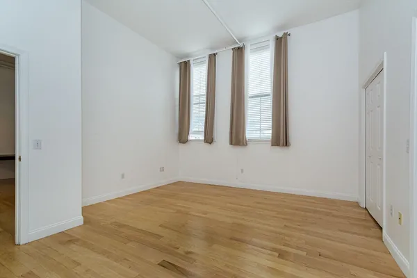 an empty room with wooden floor and windows