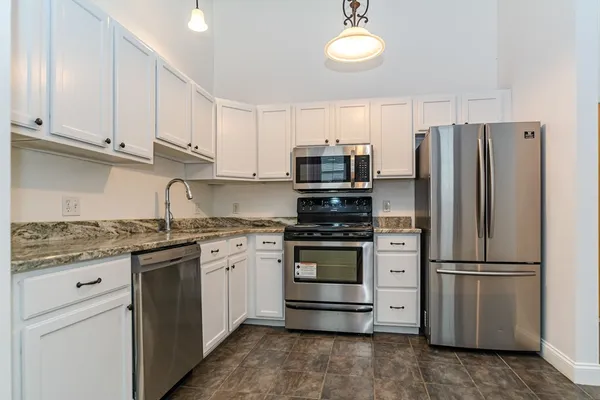 a kitchen with granite countertop white cabinets and stainless steel appliances