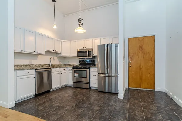 a kitchen with a refrigerator a sink and white cabinets