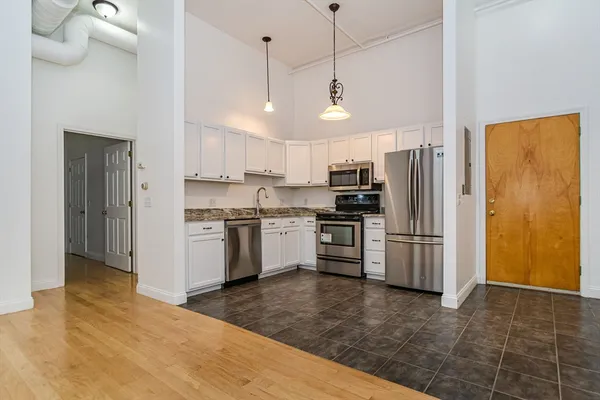 a kitchen with stainless steel appliances a refrigerator a stove a sink a center island and chairs