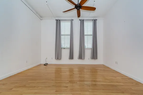 an empty room with a window and a ceiling fan