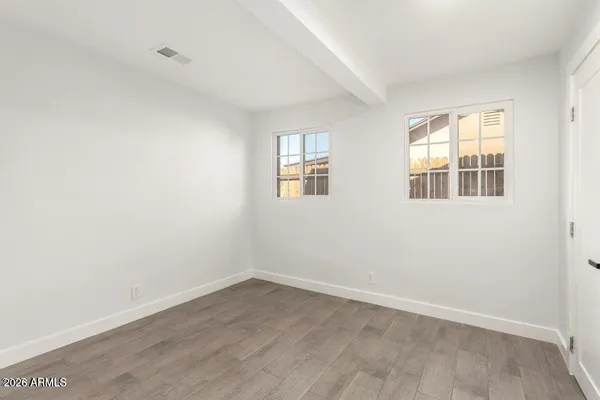 an empty room with wooden floor and windows