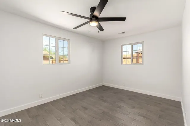 an empty room with a window and a fan